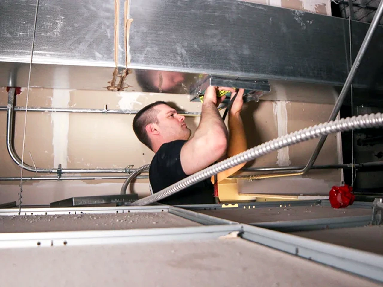 Technician servicing overhead metal air ductwork