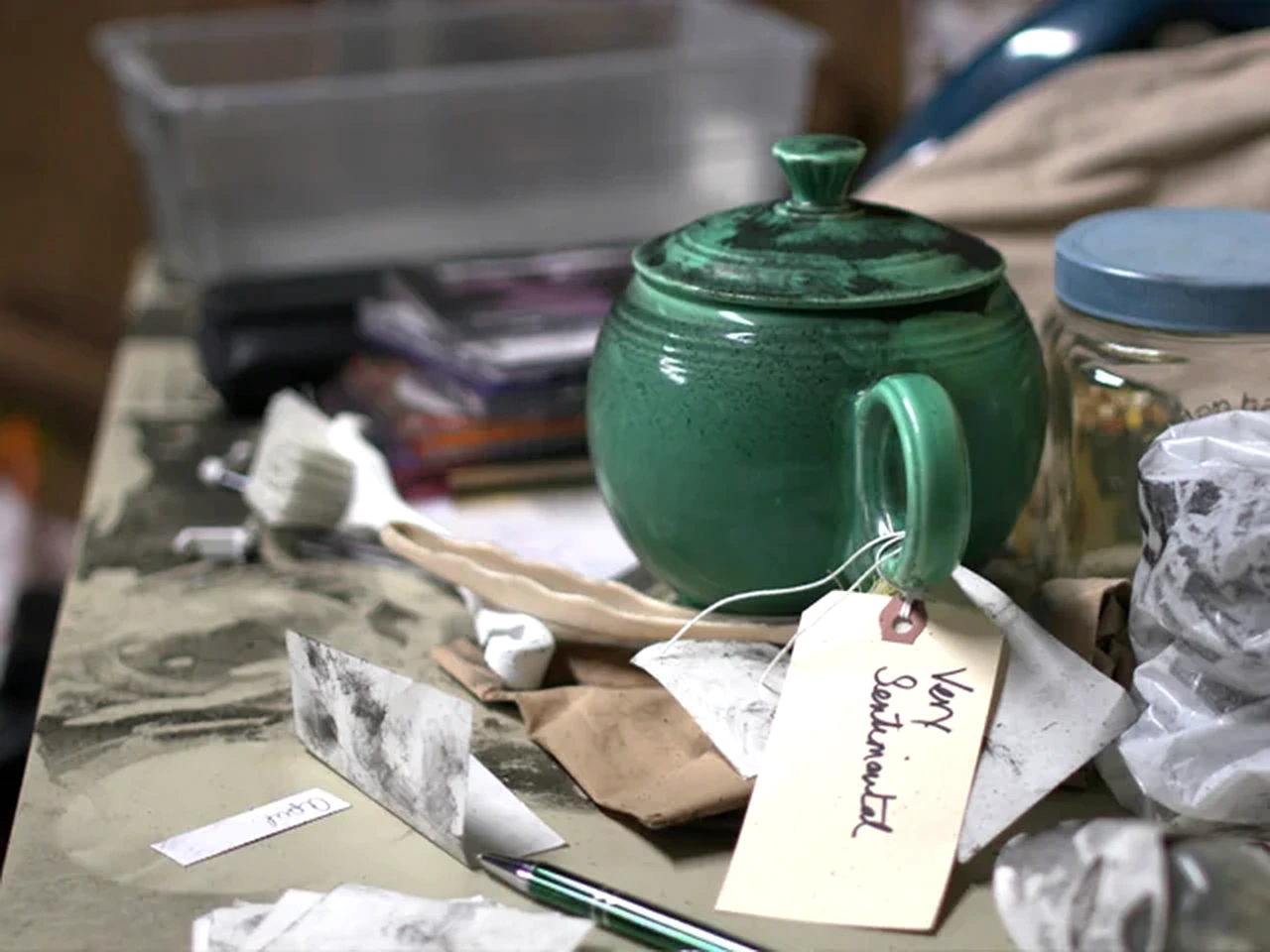Tagged green teapot and household items on a restoration workbench